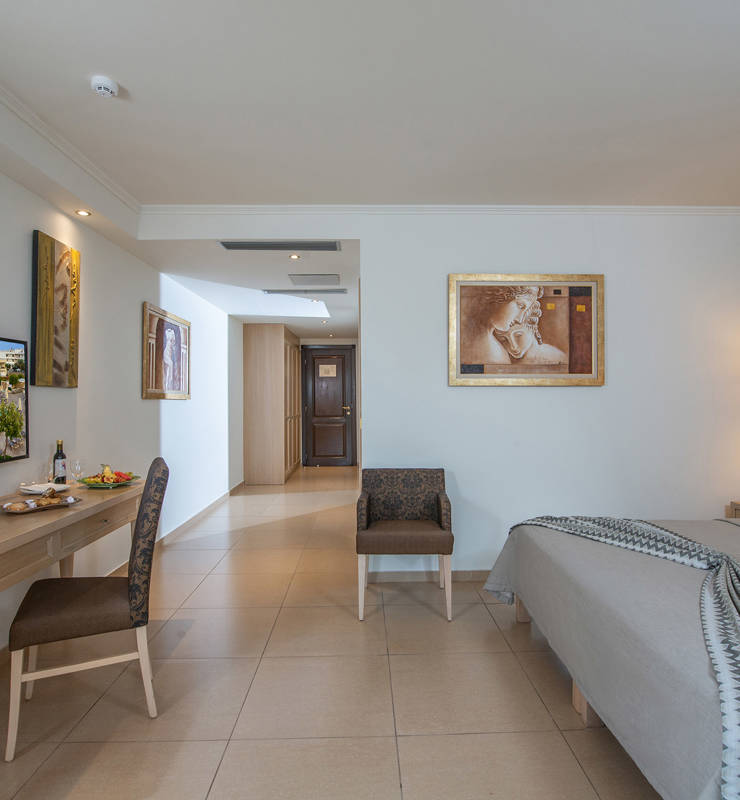 Hotel room with white color with table chairs TV clock and with green wallpaper